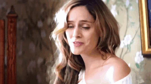 a woman in a white off the shoulder top is looking down