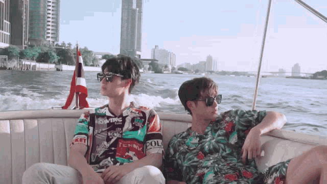 two men are sitting on a boat with one wearing a shirt that says pol