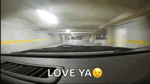 a car driving through a parking garage with the words love ya written on the dashboard