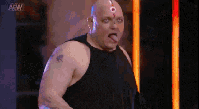 a bald man with a tattoo on his arm is sticking his tongue out