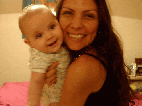 a woman is smiling while holding a baby