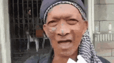 an elderly man wearing a scarf around his neck is making a funny face .