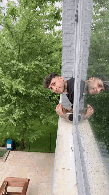 a man is looking out of a window and his reflection is in the window