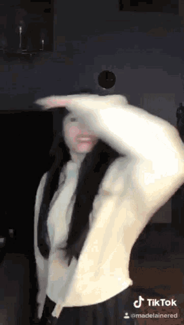 a woman in a white sweater is dancing on a tiktok video
