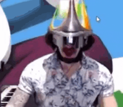 a man wearing a party hat is playing a piano .