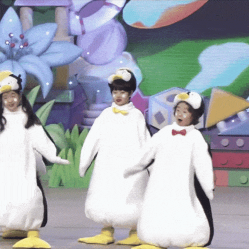 a group of children dressed in penguin costumes are dancing on a stage