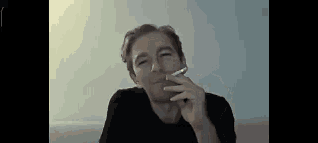 a man is smoking a cigarette in front of a camera .