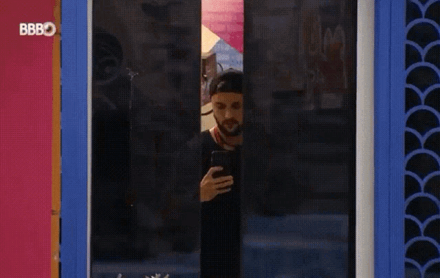 a man looking through a window with the letters bb on the bottom