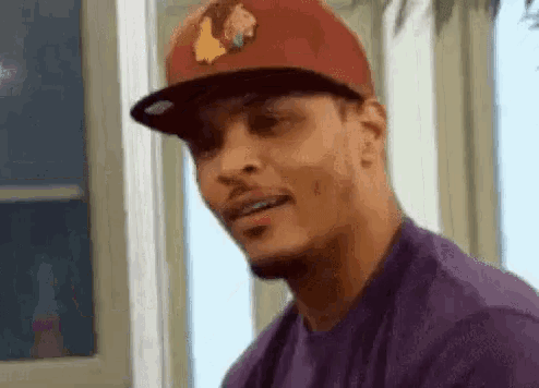 a man wearing a red baseball cap and a purple shirt is making a funny face .