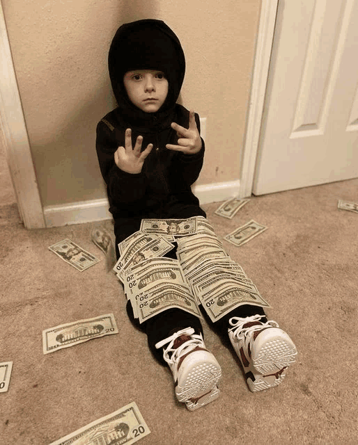 a child is sitting on the floor with a pile of 20 dollar bills around him