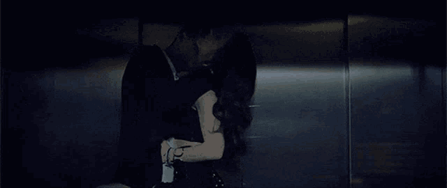 a man and a woman are kissing in a dark room .