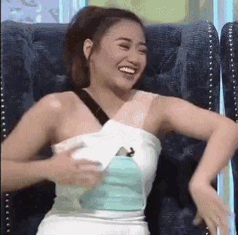 a woman in a white dress is sitting in a chair laughing and dancing .