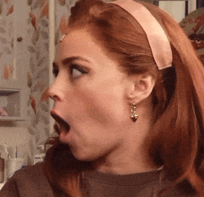 a woman with red hair wearing a headband and earrings looks surprised