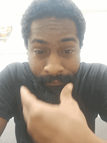 a man with a beard wearing a black shirt looks at the camera