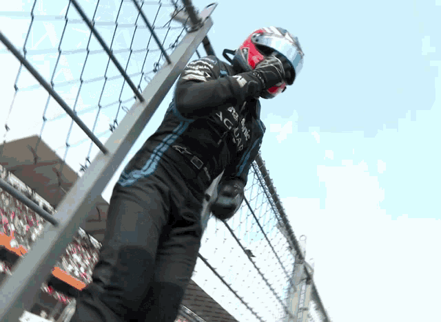 a man wearing a helmet that says jaguar stands behind a fence