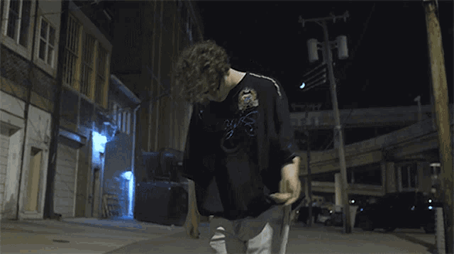 a man in a black shirt is standing in an alley at night