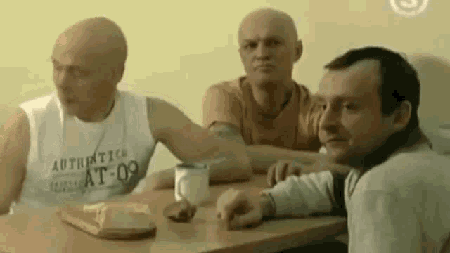 a group of men are sitting at a table with a sandwich on it .