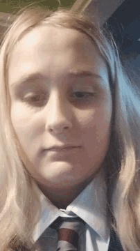 a close up of a girl 's face wearing a white shirt and tie