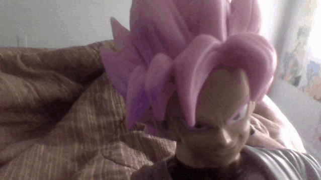 a figurine of a person with pink hair is laying on a bed