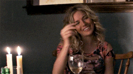 a woman sits at a table with a glass of wine and candles