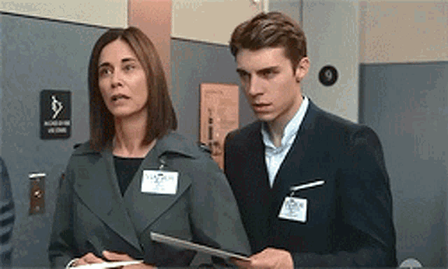 a man and a woman are standing next to each other in front of a sign that says elevator