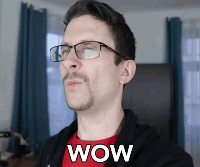 a man wearing glasses and a red shirt has the word wow on his chest