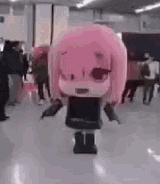 a pink mascot is dancing in a crowded room .