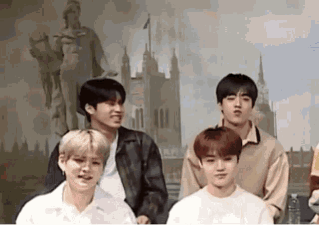 a group of young men are standing next to each other in front of a statue of a man .