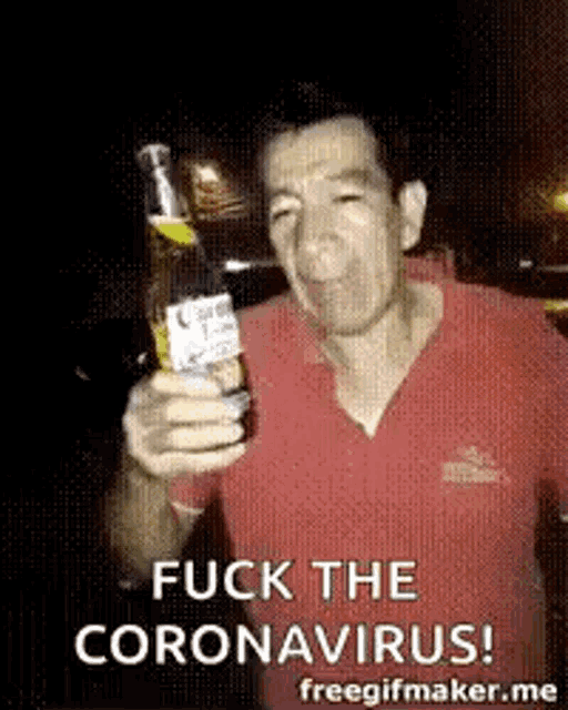a man in a red shirt is holding a bottle of beer and making a funny face .