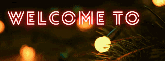 a neon sign that says welcome to y with christmas lights in the background