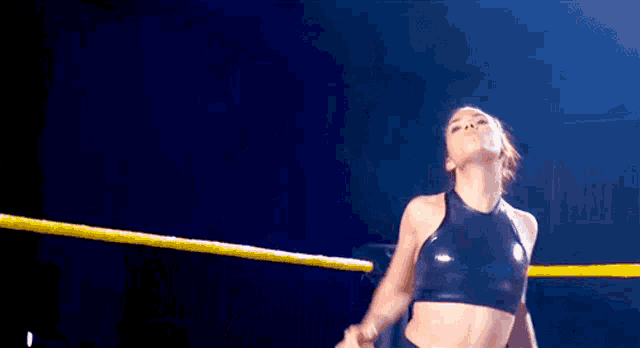 a woman is standing in a wrestling ring with a yellow rope around her waist .