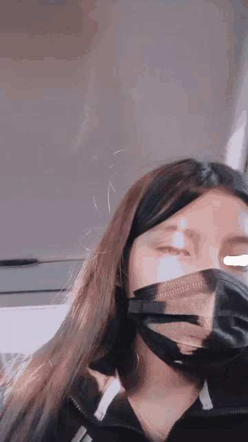 a woman wearing a black face mask with a reflection of her face in it