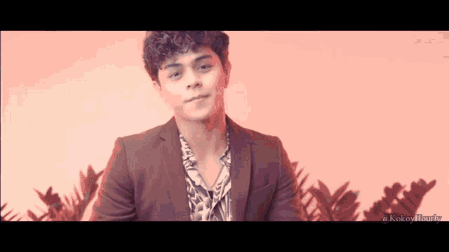 a young man in a suit and hawaiian shirt is smiling