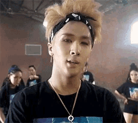 a young man wearing a headband and a necklace is making a funny face in a dance studio .