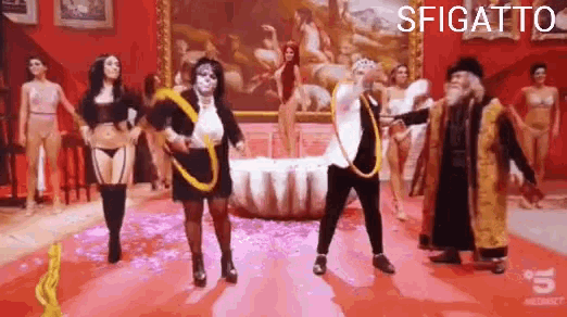 a group of people are dancing in front of a painting and the word sfigato is on the bottom