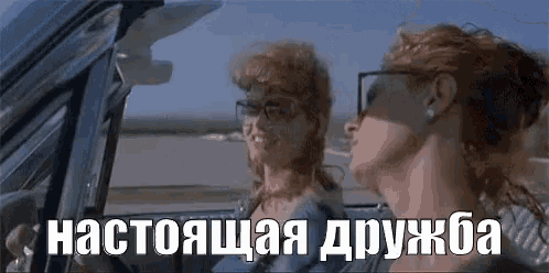 two women are sitting in a car with russian writing on the side .