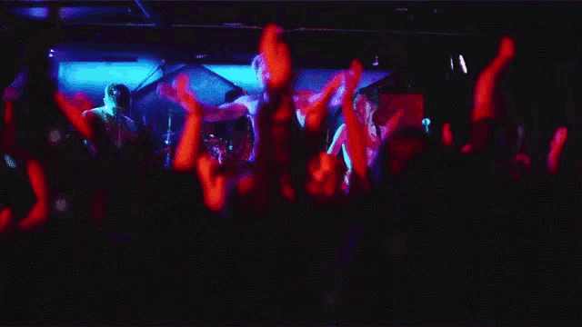 a crowd of people raising their arms in the air at a concert