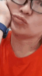 a close up of a person wearing glasses and a red shirt making a funny face .