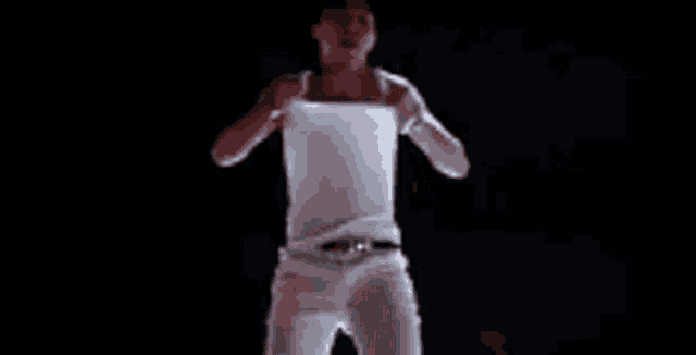 a man without a shirt is standing in a dark room with his shirt off .