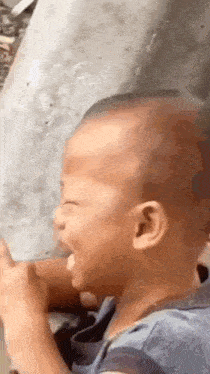 a baby is laughing while sitting on the ground with his mouth open .