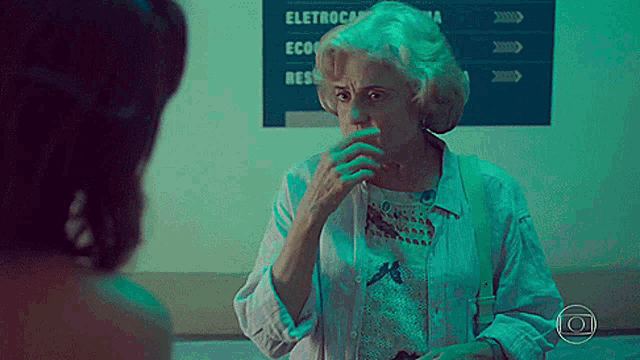 an elderly woman is talking to a younger woman in front of a sign that says eletroca