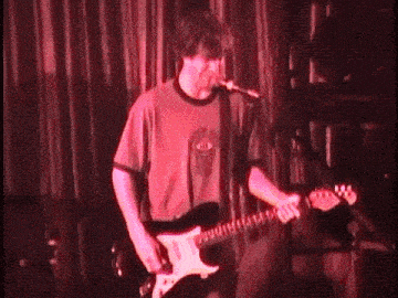 a man singing into a microphone while playing an electric guitar