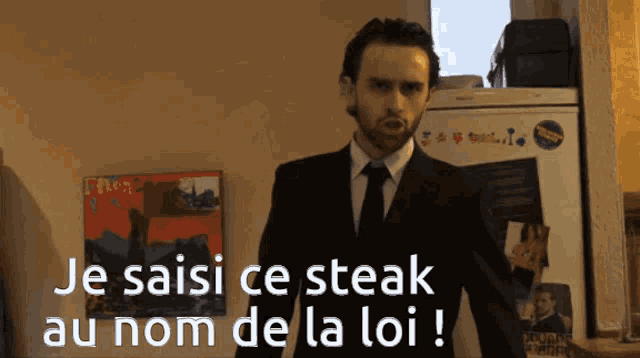 a man in a suit and tie is standing in front of a refrigerator that says je saisi ce steak au nom de la loi
