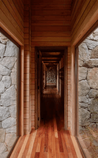 a hallway with a wooden floor and a stone wall in the background