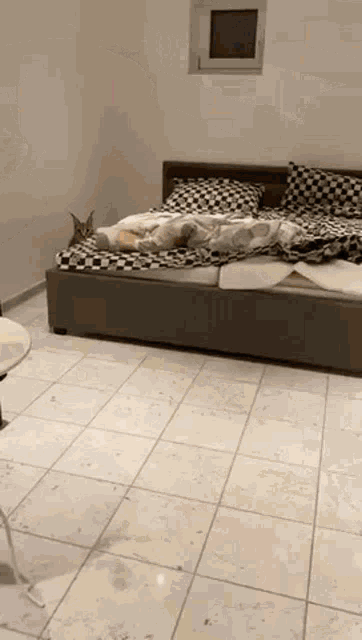 a cat is laying on a bed in a room with a tiled floor .