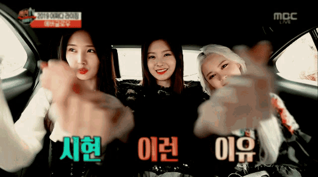 three girls are sitting in a car with chinese writing on the screen