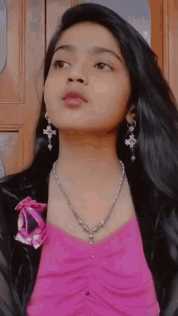 a young girl wearing a necklace and earrings looks up