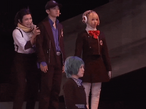 a group of people are dancing on a stage and one of them is wearing a hat with the letter b on it