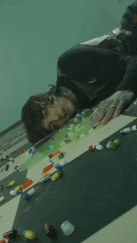 a man is laying on a table surrounded by pills and capsules