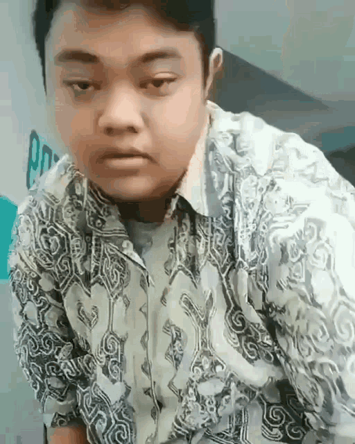 a young man in a floral shirt is making a funny face .